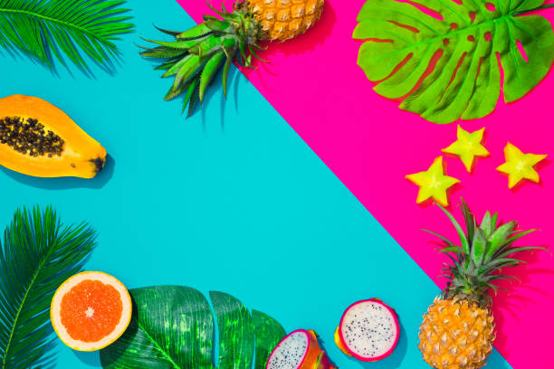 Creative tropical layout with tropical fruit. leaves and colorful vivid papers. Abstract colors art background. Minimal summer concept. Flat lay.