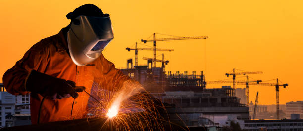 istock Industrial worker welding steel structure for infrastructure building project with construction site in background. 1007090492