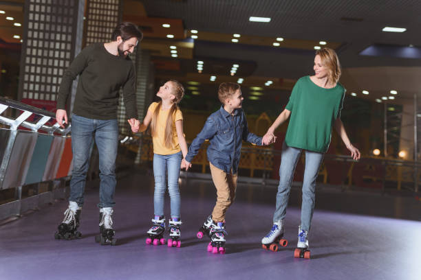 glückliche familie hand in hand beim skaten gemeinsam auf der rollschuhbahn - rollschuh stock-fotos und bilder