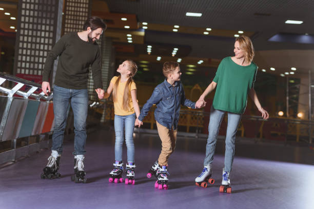 happy family holding hands while skating together on roller rink happy family holding hands while skating together on roller rink roller rink stock pictures, royalty-free photos & images