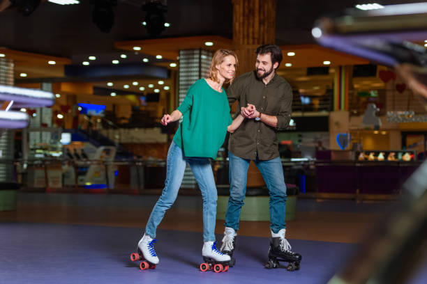 young couple holding hands while skating together on roller rink young couple holding hands while skating together on roller rink roller rink stock pictures, royalty-free photos & images
