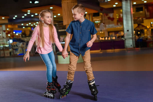 adorable kids holding hands while skating together on roller rink adorable kids holding hands while skating together on roller rink roller rink stock pictures, royalty-free photos & images