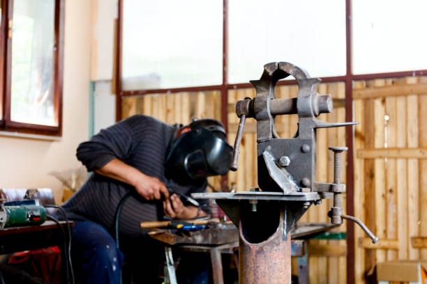 istock Mechanical hand vise with parallel jaws in the metalwork, craftsman welding in background 1007098028