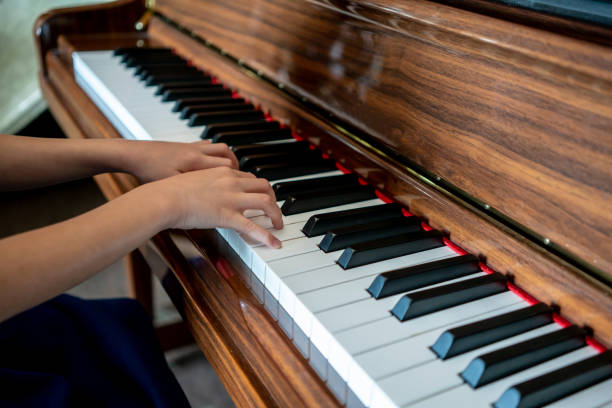 istock Kid hands on upright wooden piano. Selective focus. 1007098830