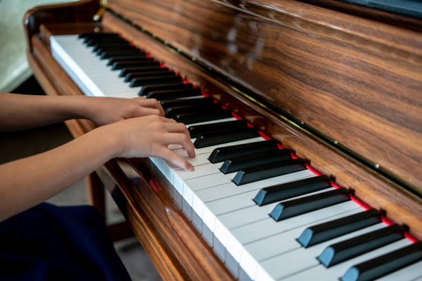 Kid hands on upright wooden piano. Selective focus. stock photo