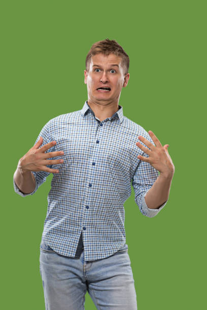 istock The young attractive man looking suprised isolated on green 1007101062