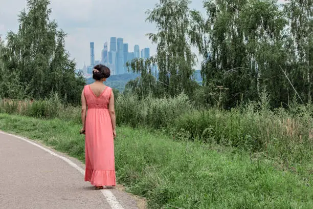 Nature and city - girl in the park against skyscrapers and business city. Confronting the natural landscape and urban architecture.