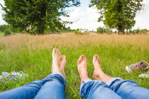 Young couple relaxing feet in a grass field.