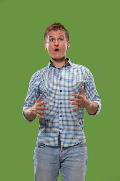istock The young attractive man looking suprised isolated on green 1007130292