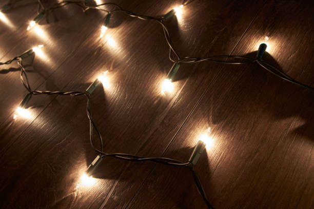 istock Traditional Christmas Tree lights lying on a wooden floor. 1007130528