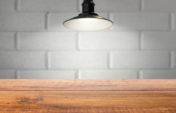 istock Old studio professional lighting template for product display.  Aged wooden table and faded old brick.  Classic hanging light. 1007148998