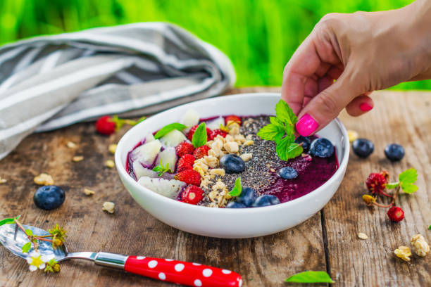 istock Females hands putting berries into smoothie bowl 1007151610