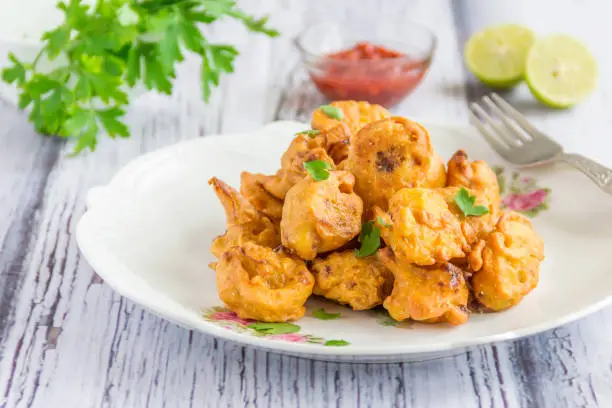 Indian Snack - Cauliflower Fritter / Pakora Served with Cilantro and Lemon.l