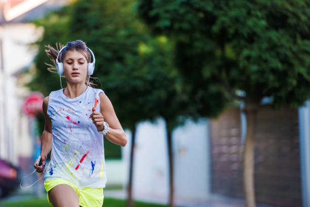 jeune femme avec un casque jogging en banlieue - beautiful caucasian teenager running photos et images de collection