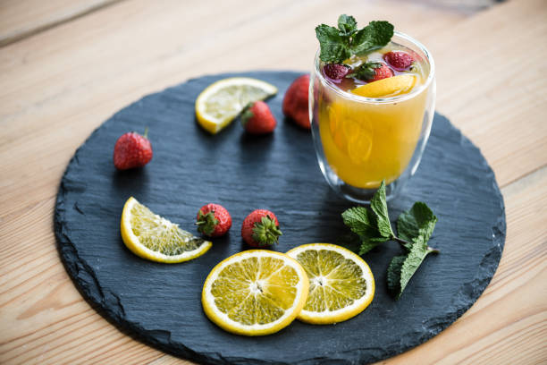 fruity summer cocktail with strawberries and mint in glass on slate board