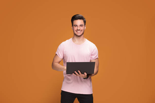 istock Happy young man with laptop on yellow background. 1007159872