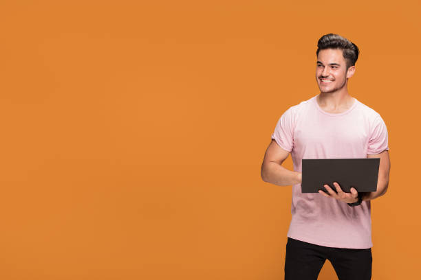istock Happy young man with laptop on yellow background. 1007160032
