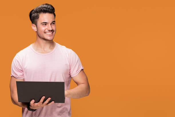 istock Happy young man with laptop on yellow background. 1007160094
