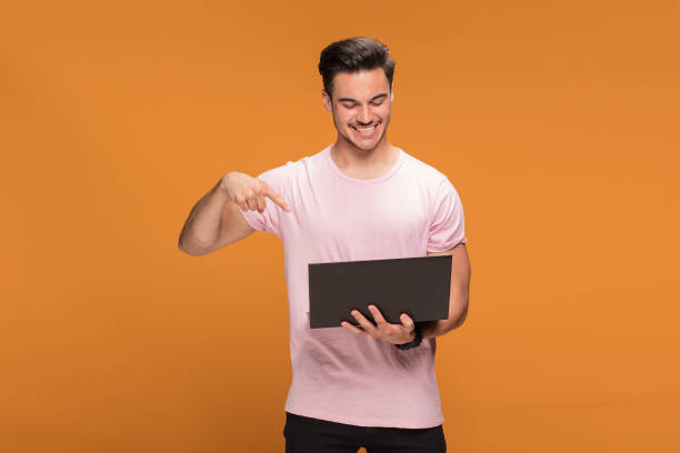 istock Happy young man with laptop on yellow background. 1007160190