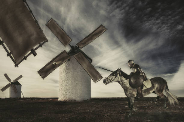 don quijote carga con su caballo contra molinos de viento la proyección de imagen son gigantes - run of the mill fotografías e imágenes de stock