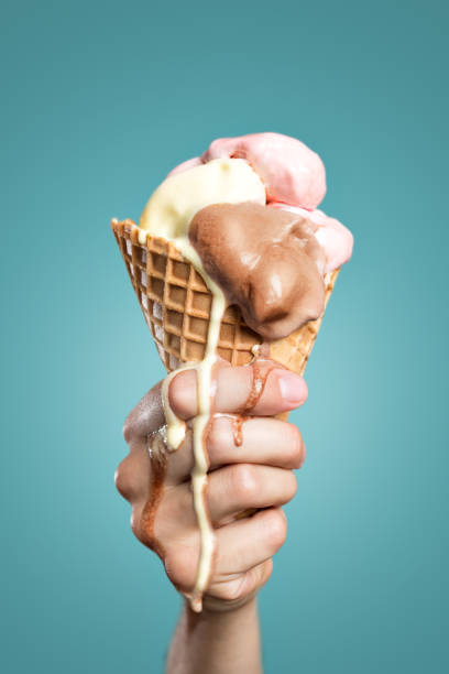 Melting ice cream cone A hand is holding a large ice cream cone. The ice cream is melting down the hand. melting stock pictures, royalty-free photos & images