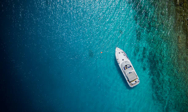 Luxury small yacht anchoring in shallow water Luxury small yacht anchoring in shallow water, aerial view. Active life style, water transportation and marine sport. yacht stock pictures, royalty-free photos & images