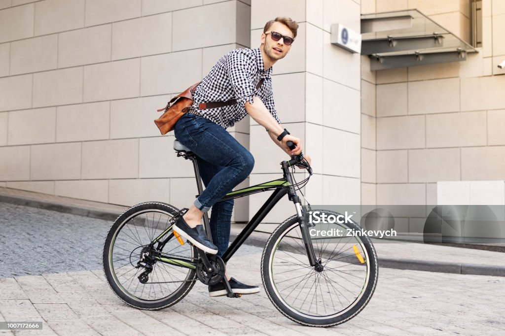 Smart handsome man riding a bike in the city Fast vehicle. Smart handsome man riding a bike in the city while going to work in the office Cycling Stock Photo