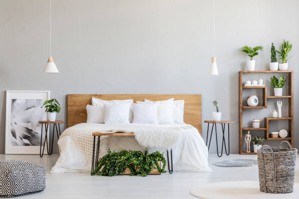 cesta interior dormitorio luminoso con lámparas, plantas y carteles junto a la cama y puf estampado. foto real - cultura escandinava fotografías e imágenes de stock