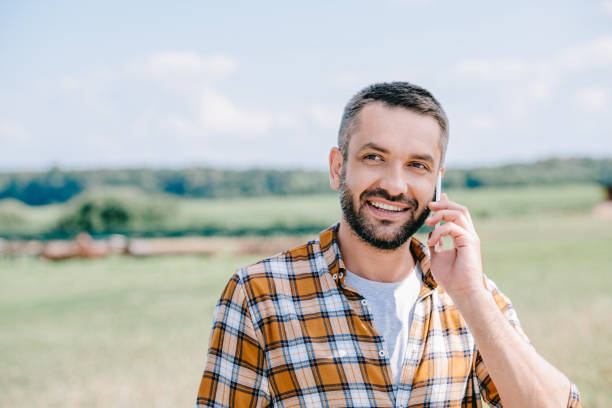 istock smiling middle aged farmer talking by smartphone in field 1007188922