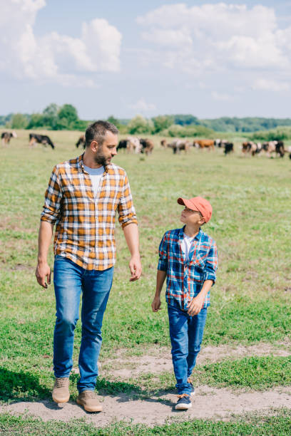 happy father and son walking on field and looking at each other - boyhood imagens e fotografias de stock