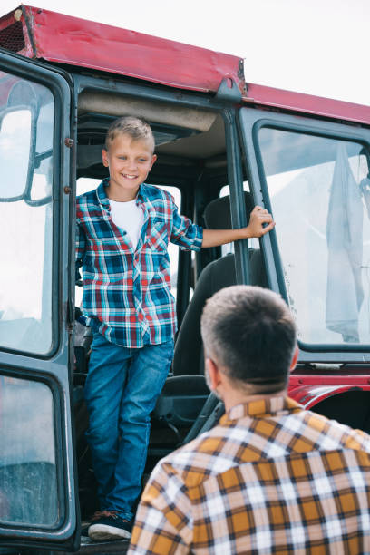 istock back view of father looking at happy son standing in tractor 1007189130