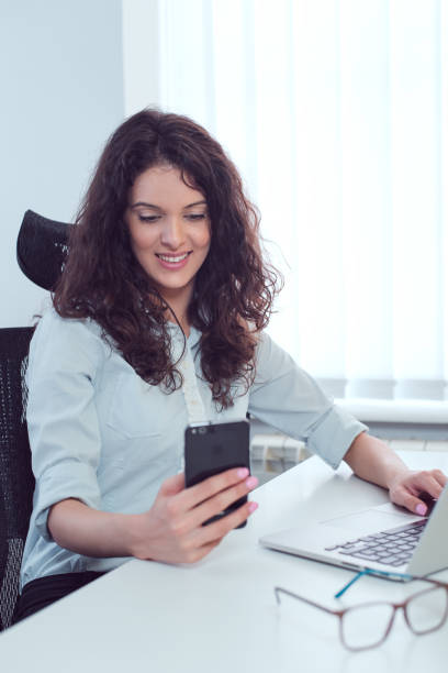 istock Happy woman at work texting using smart phone 1007189940
