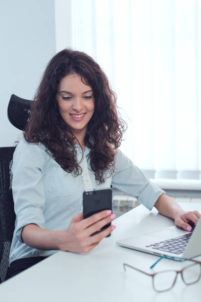 istock Happy woman in office texting using smart phone 1007189964