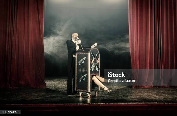 Magician Inserting Swords In Box Occupied By Female Assistant Stock Photo - Download Image Now