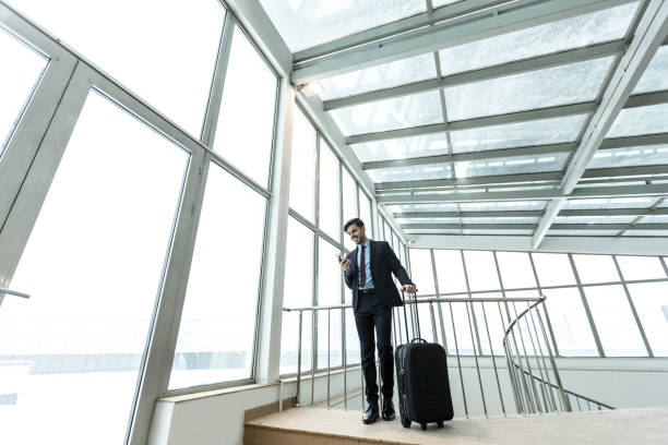 istock Eegant man with luggage using smart phone 1007194120