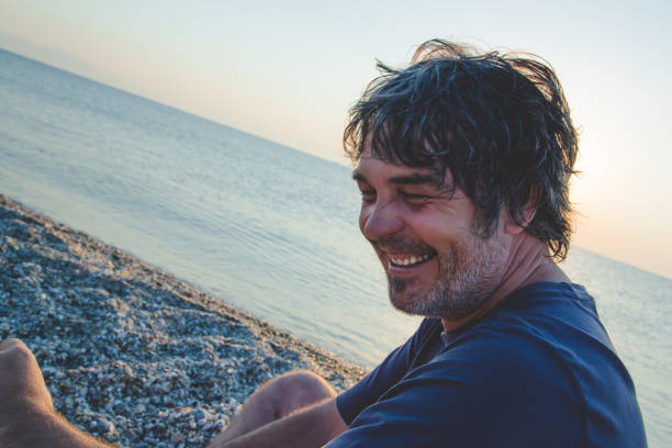 istock Handsome man relaxing on the beach in Greece while sunsets 1007194428