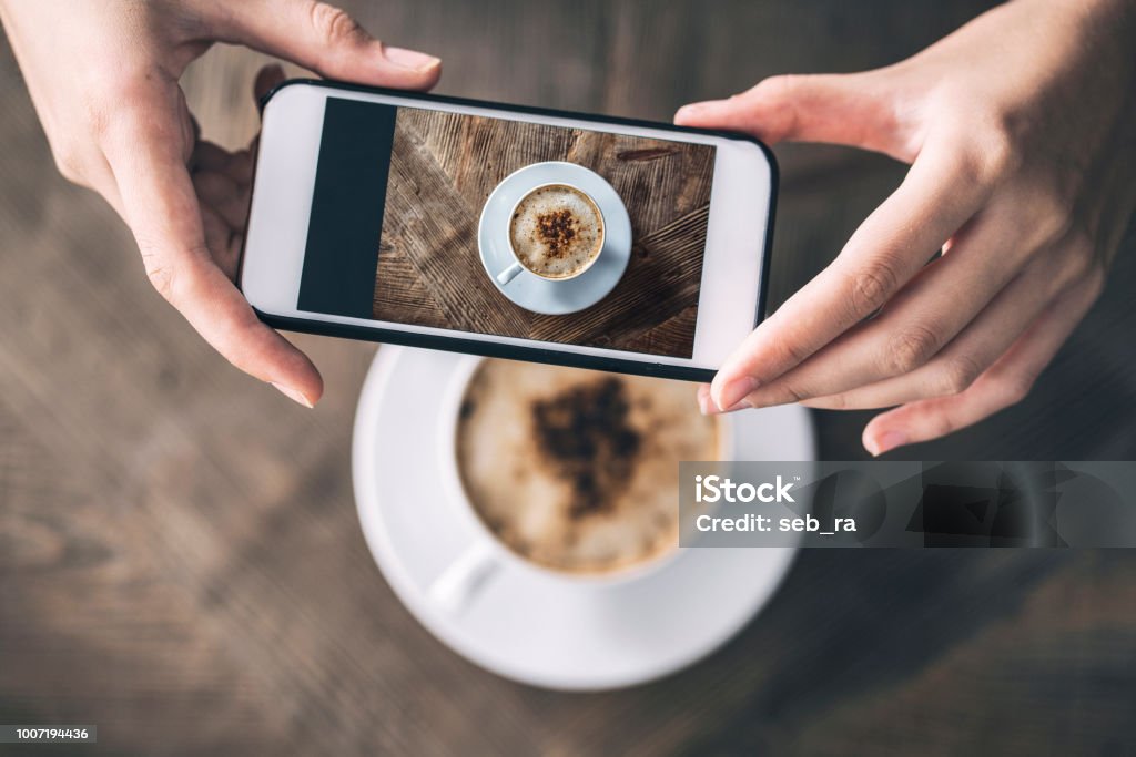 Woman taking a picture of a coffee cup with her mobile phone Coffee - Drink Stock Photo
