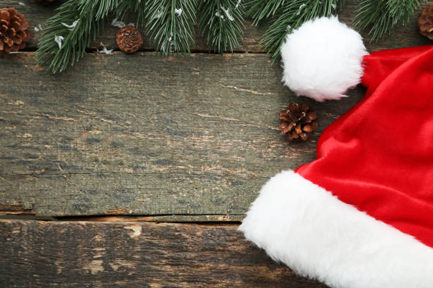 istock Red santa hat with fir-tree branch and cones on grey wooden table 1007199068