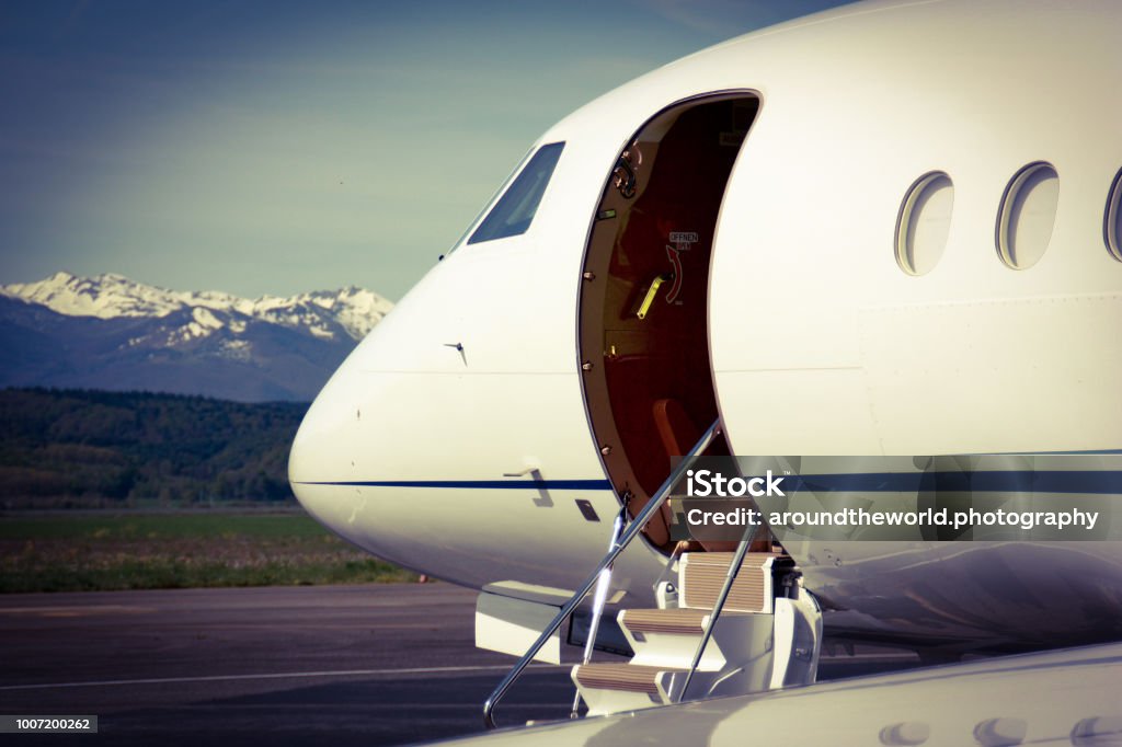 Falcon Business Jet waiting for Customers A Falcon 2000 Business Jet waiting for passengers in Lourde, France. In the background the beautiful and snow covered Pyrenees are rising up. Corporate Jet Stock Photo