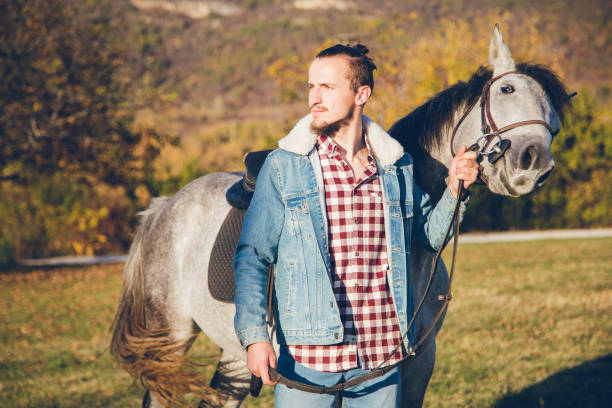 istock Man with grey horse at sunset 1007210690
