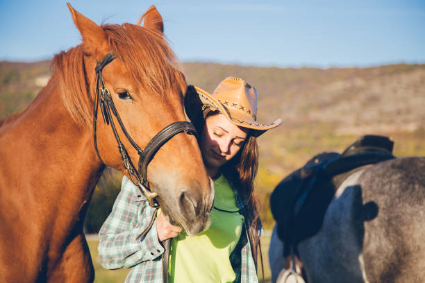 istock Cowgirl standing between two horses at sunset 1007211168