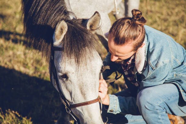 istock Man with grey horse at sunset 1007215102