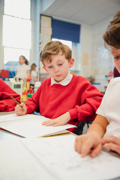 uczeń pracujący w swojej klasie podstawowej - workbook education school uniform child zdjęcia i obrazy z banku zdjęć