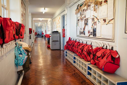A corridor can be seen in a school where backpacks are hung in a row against the wall. This is a school in Hexham, Northumberland in north eastern England.