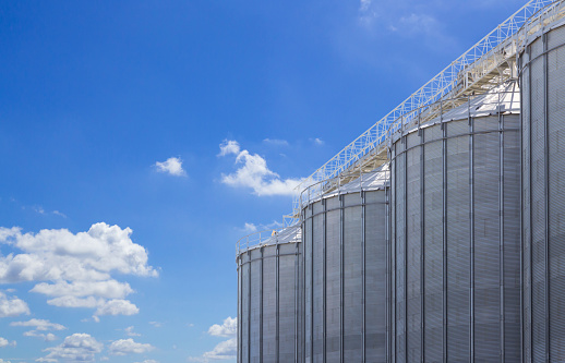 agriculture tank against blue sky background, seed steel silos, grain metal storage container.