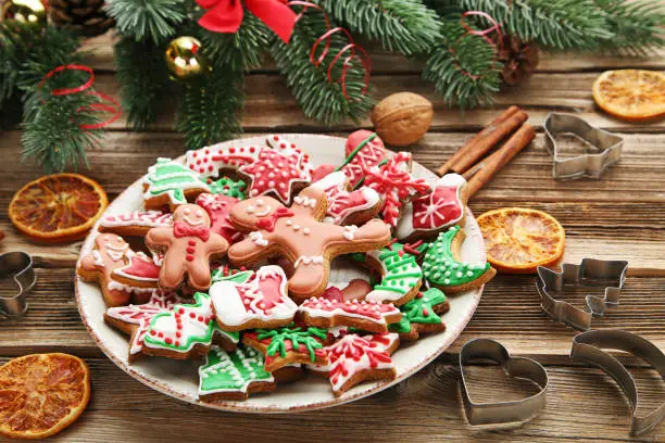 Christmas gingerbread cookies in plate with fir-tree branch on wooden table