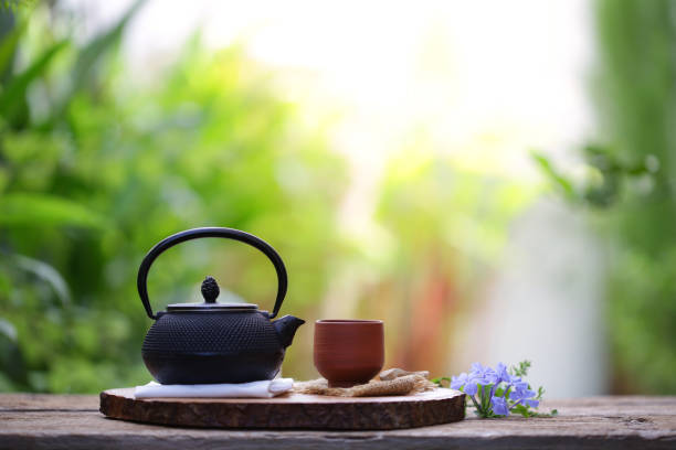 istock Old black tea pot with brown cup and flower 1007227268