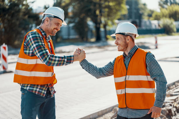 istock Smiling workers in reflective vests and white helmets holding hands 1007229792