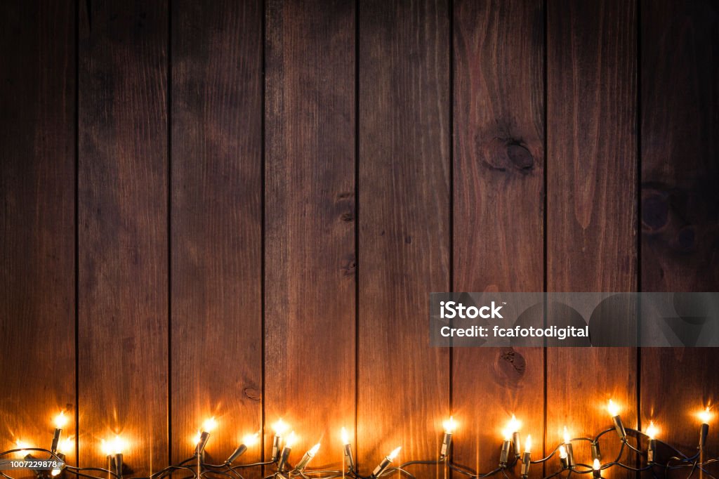 Empty rustic wooden table with Christmas lights border Top view of an empty rustic wooden table with Christmas lights string arranged at the bottom border making a frame and leaving useful copy space for text and/or logo. Predominant colors are brown and yellow. DSRL studio photo taken with Canon EOS 5D Mk II and Canon EF 70-200mm f/2.8L IS II USM Telephoto Zoom Lens Christmas Stock Photo