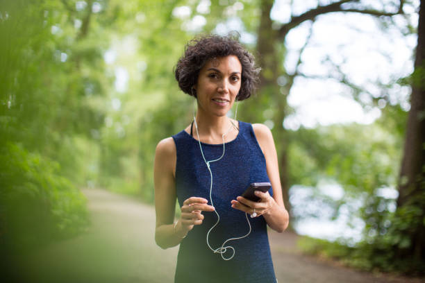 istock Woman listening to music while standing in forest 1007230262